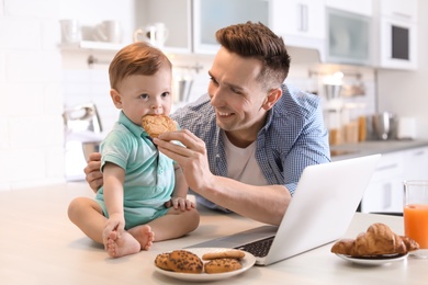 Young father and his cute little son with cookies in kitchen