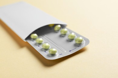 Photo of Birth control pills on beige background, closeup