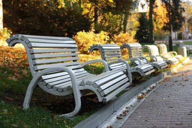 Photo of White wooden benches in park on sunny day