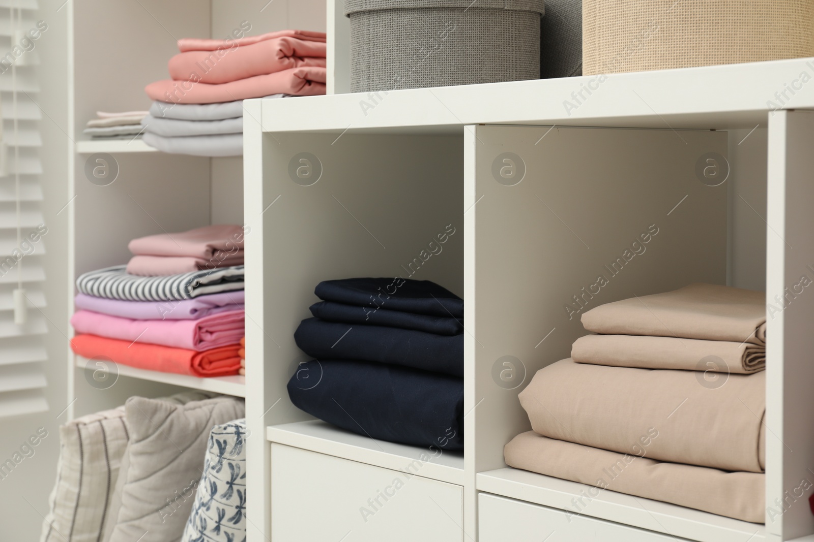 Photo of Different colorful bed linens and decorative boxes on display in home textiles store