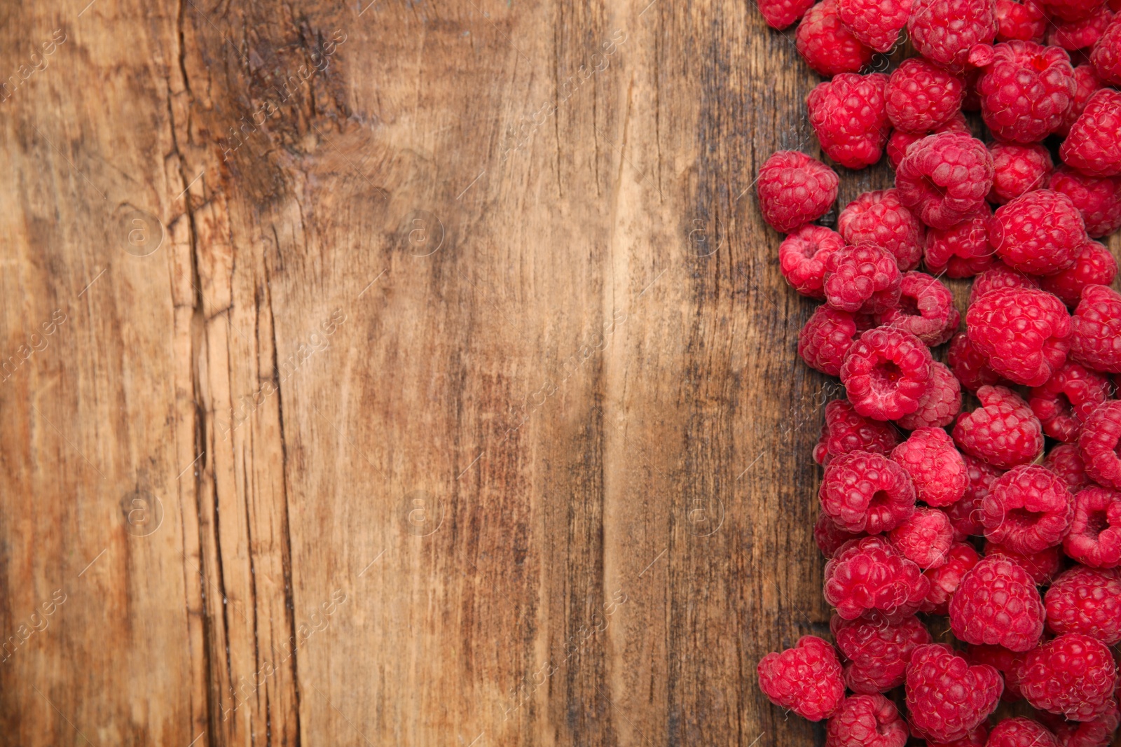 Photo of Fresh ripe raspberries on wooden table, flat lay. Space for text