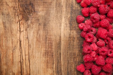 Photo of Fresh ripe raspberries on wooden table, flat lay. Space for text