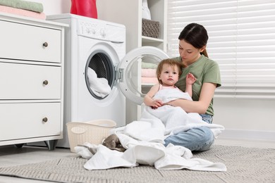 Mother with her daughter washing baby clothes in bathroom