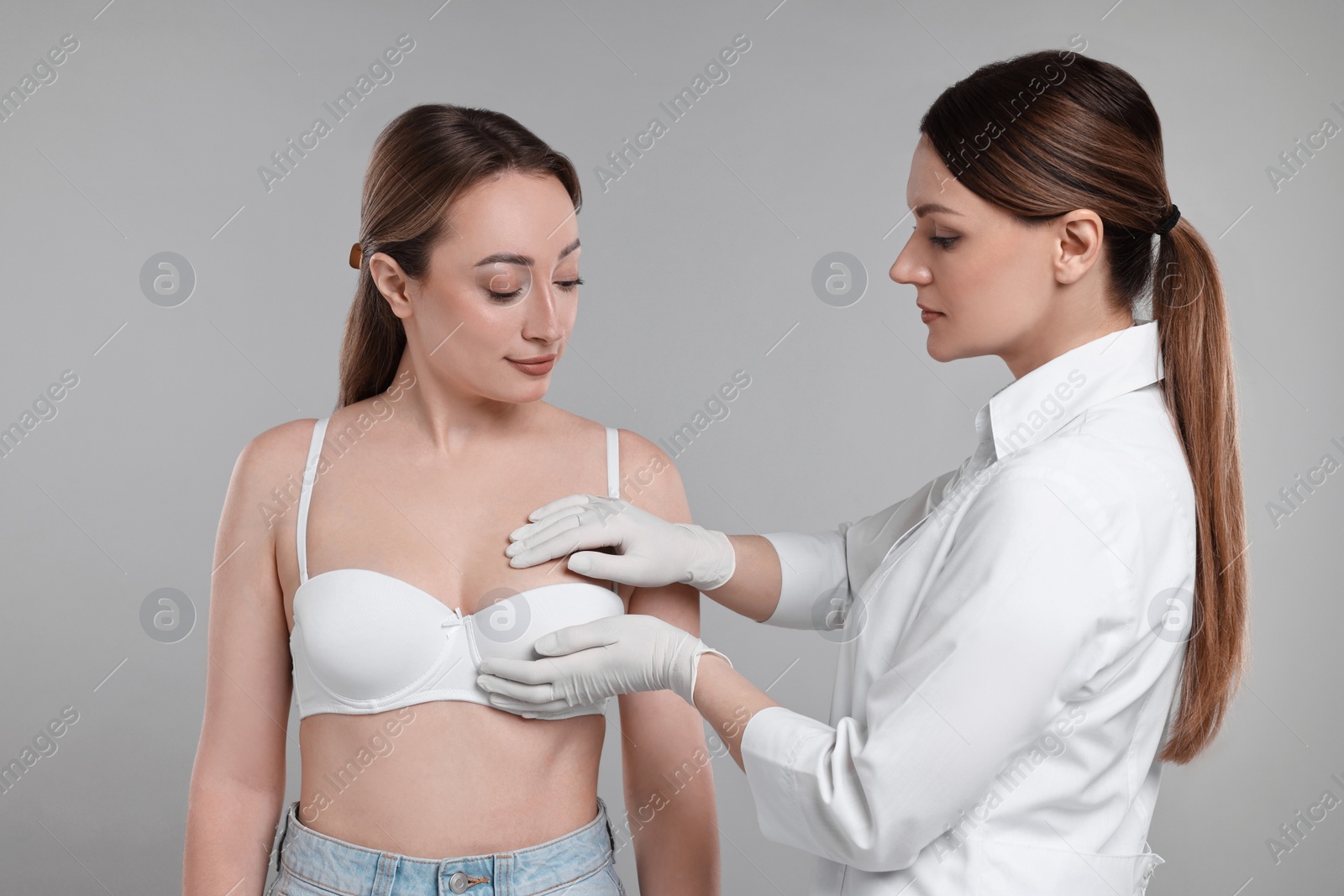 Photo of Mammologist checking woman's breast on gray background