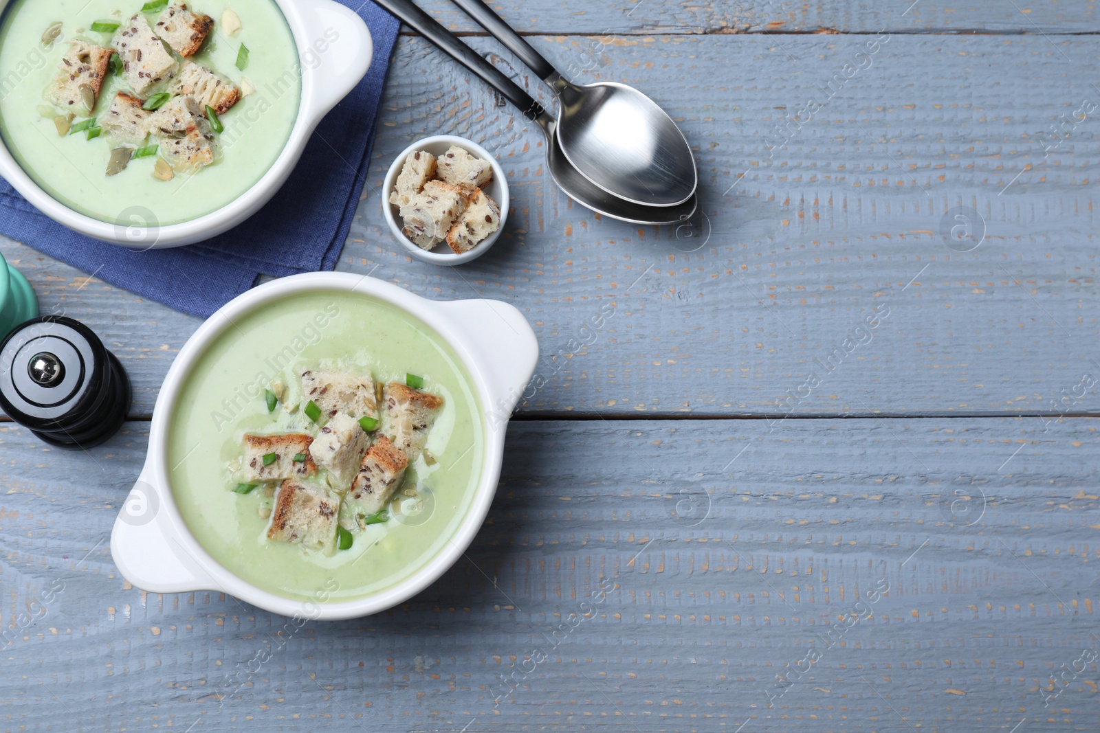 Photo of Delicious asparagus soup with croutons served on grey wooden table, flat lay. Space for text