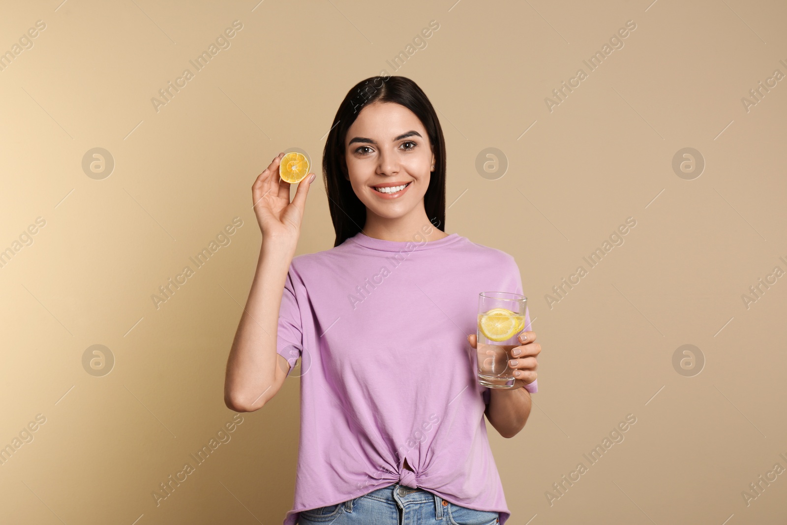 Photo of Beautiful young woman with tasty lemon water and fresh fruit on beige background