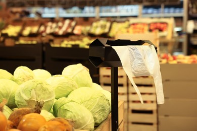 Plastic bags near rack with vegetables in supermarket
