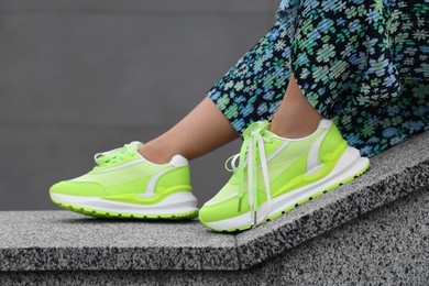 Photo of Woman wearing pair of stylish sneakers outdoors, closeup