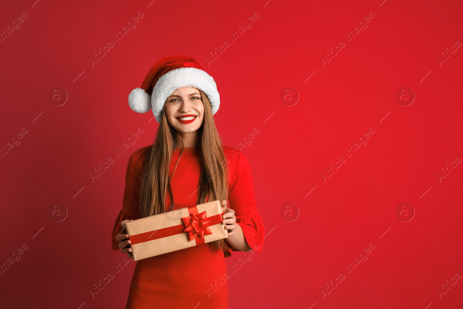 Photo of Young beautiful woman in Santa hat with gift box on color background. Christmas celebration