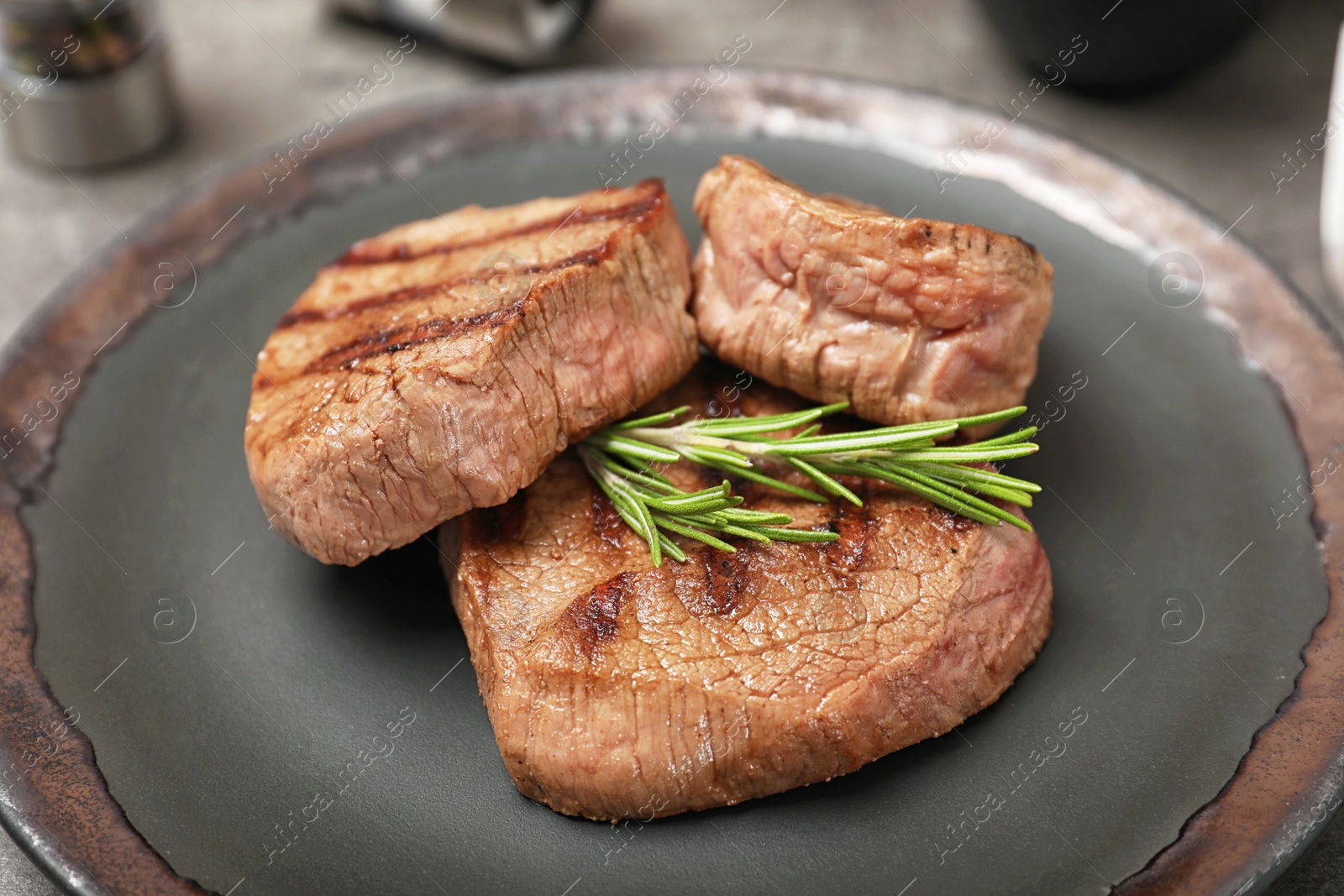 Photo of Grilled meat with rosemary on plate, closeup