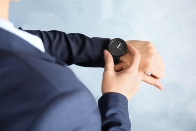 Businesswoman with stylish wrist watch on color background, closeup. Time management