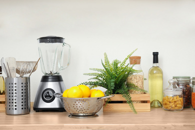 Wooden countertop with appliances and products near white wall. Kitchen interior idea