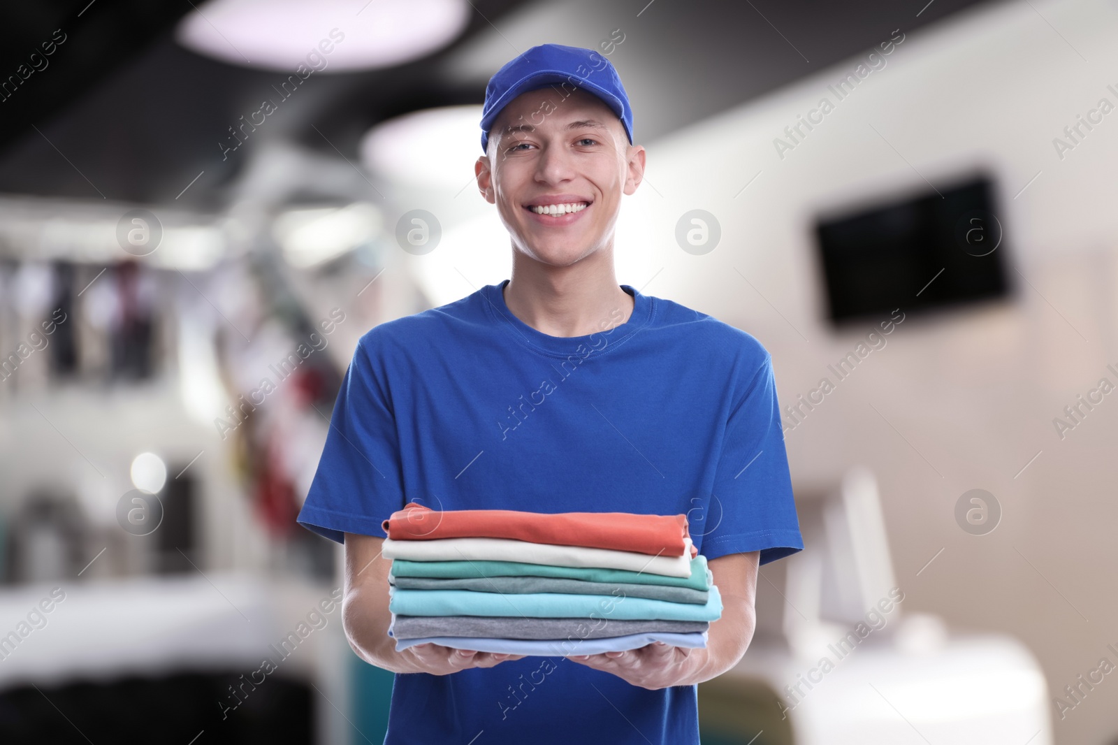 Image of Happy courier holding folded clothes in dry-cleaning