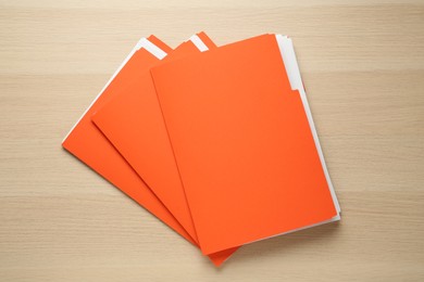 Photo of Orange files with documents on wooden table, top view