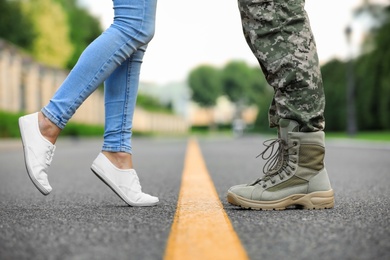 Man in military uniform and young woman separated by yellow line on road, closeup