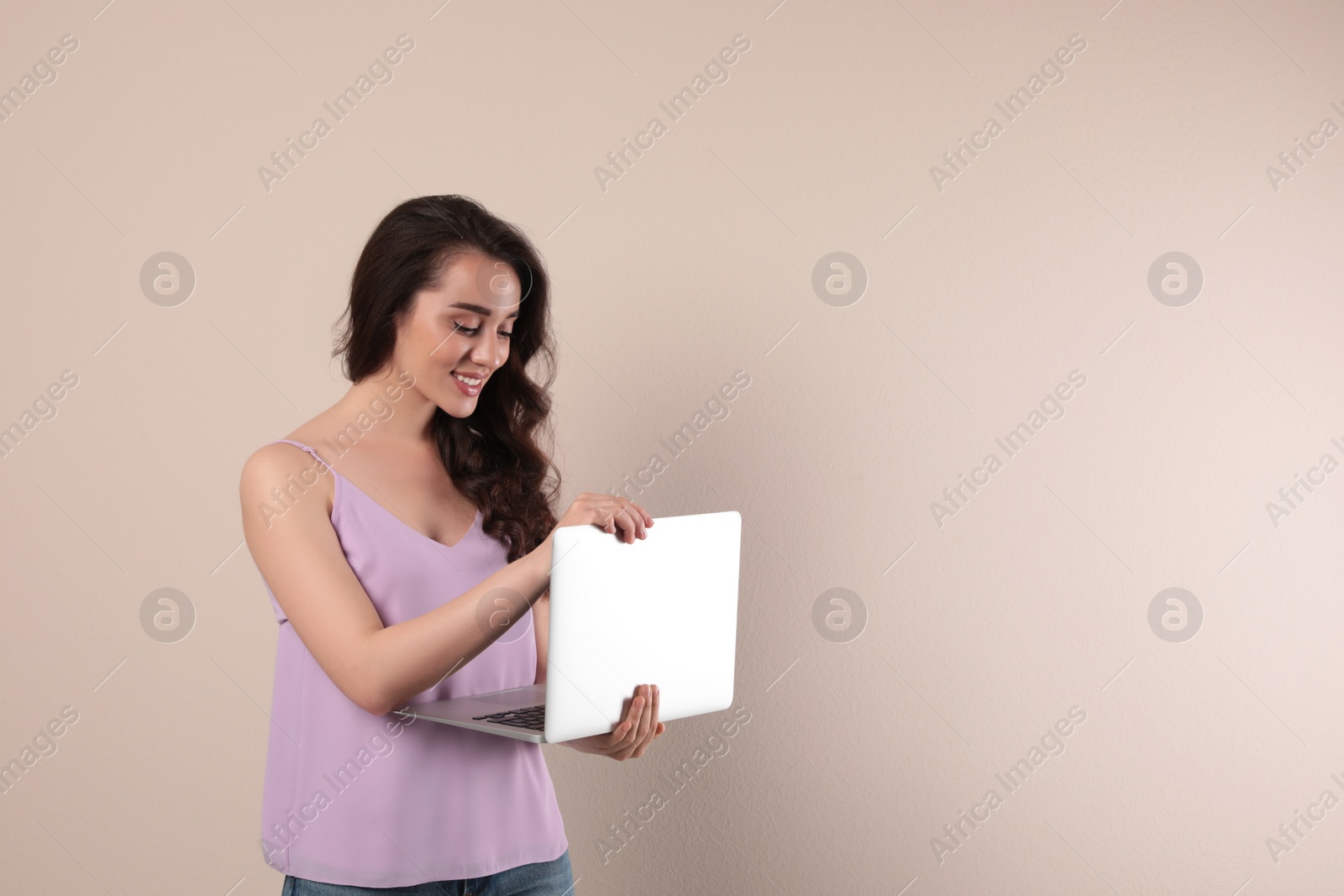 Photo of Young woman with laptop on beige background. Space for text