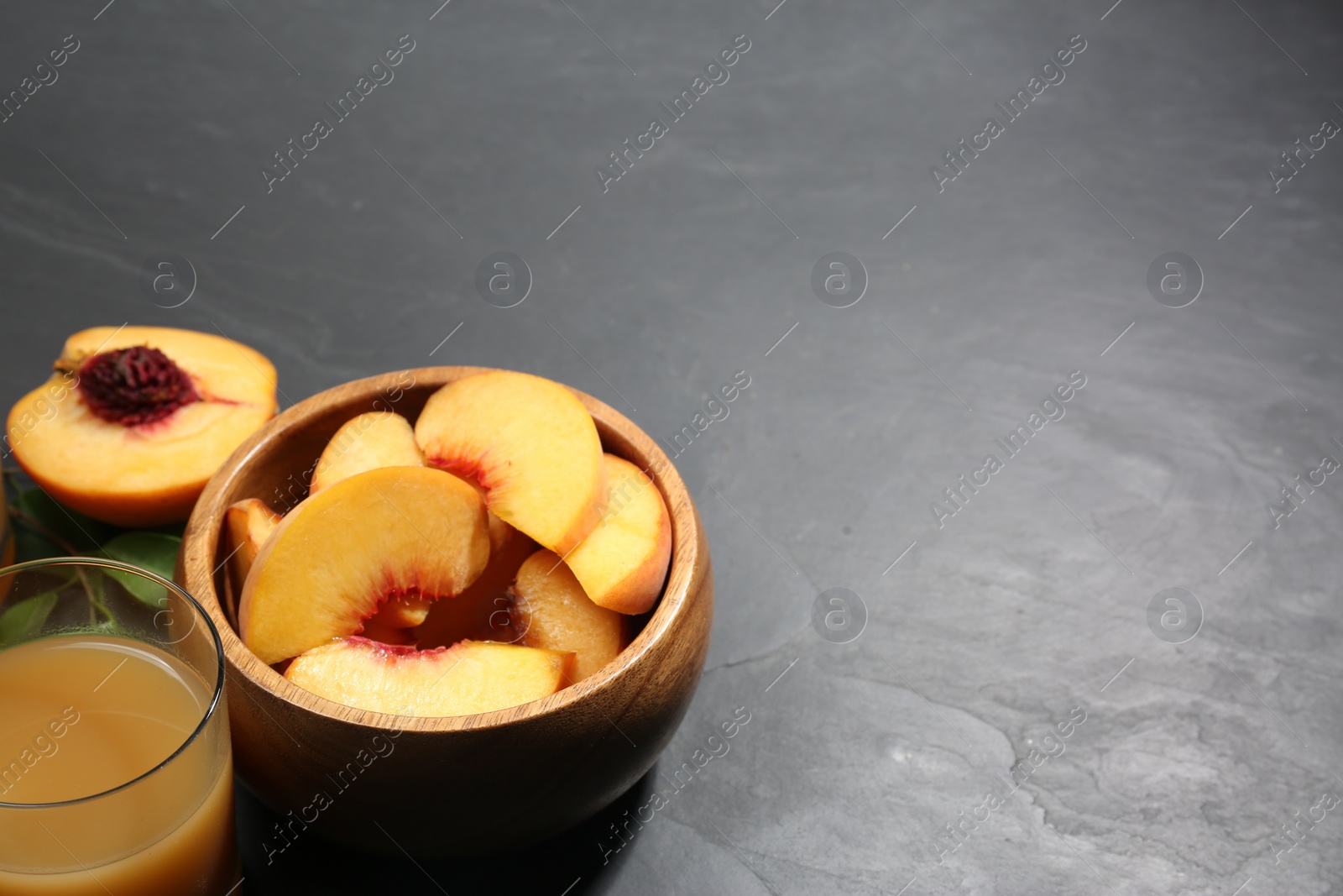 Photo of Glass of peach juice and cut fresh fruits on black table. Space for text