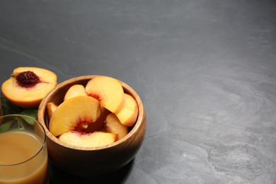 Glass of peach juice and cut fresh fruits on black table. Space for text