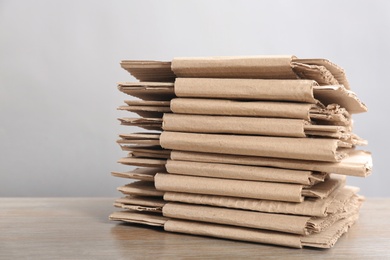 Cardboard pile on table against light background, space for text. Waste recycling concept