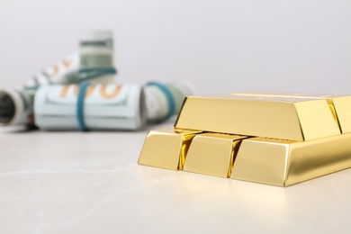 Photo of Shiny gold bars and dollar rolls on table. Space for text