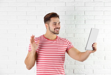 Man using tablet for video chat against brick wall