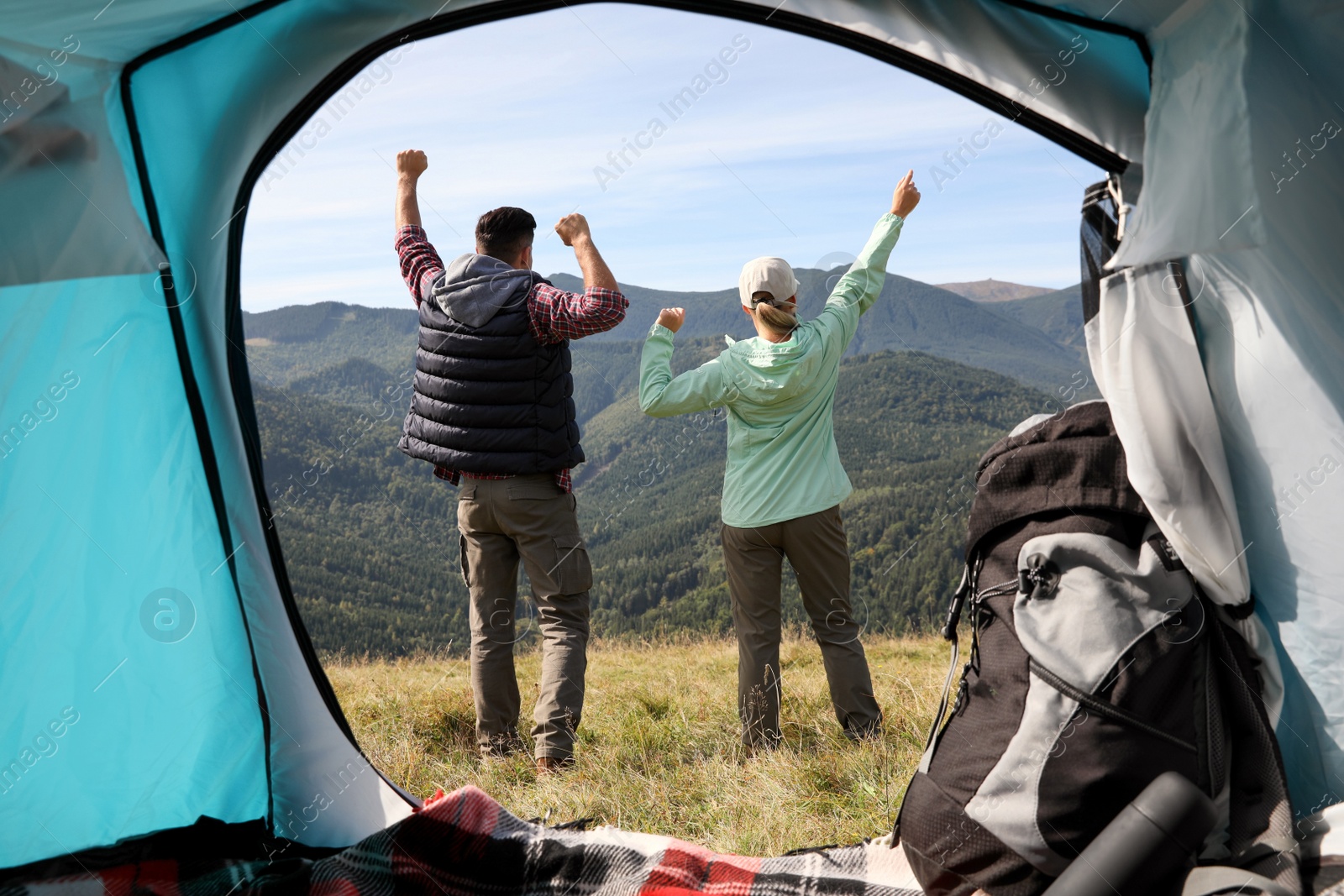 Photo of Couple in mountains on sunny day, view from camping tent