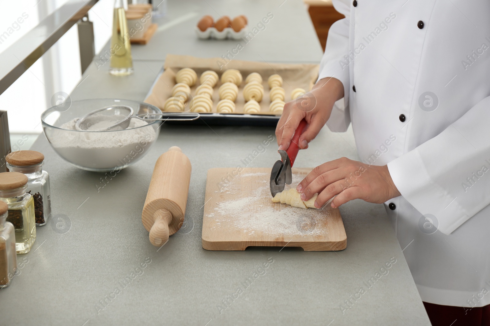 Photo of Female pastry chef preparing croissant at table in kitchen, closeup