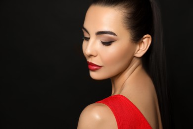 Image of Portrait of young woman wearing beautiful red lipstick on black background, space for text