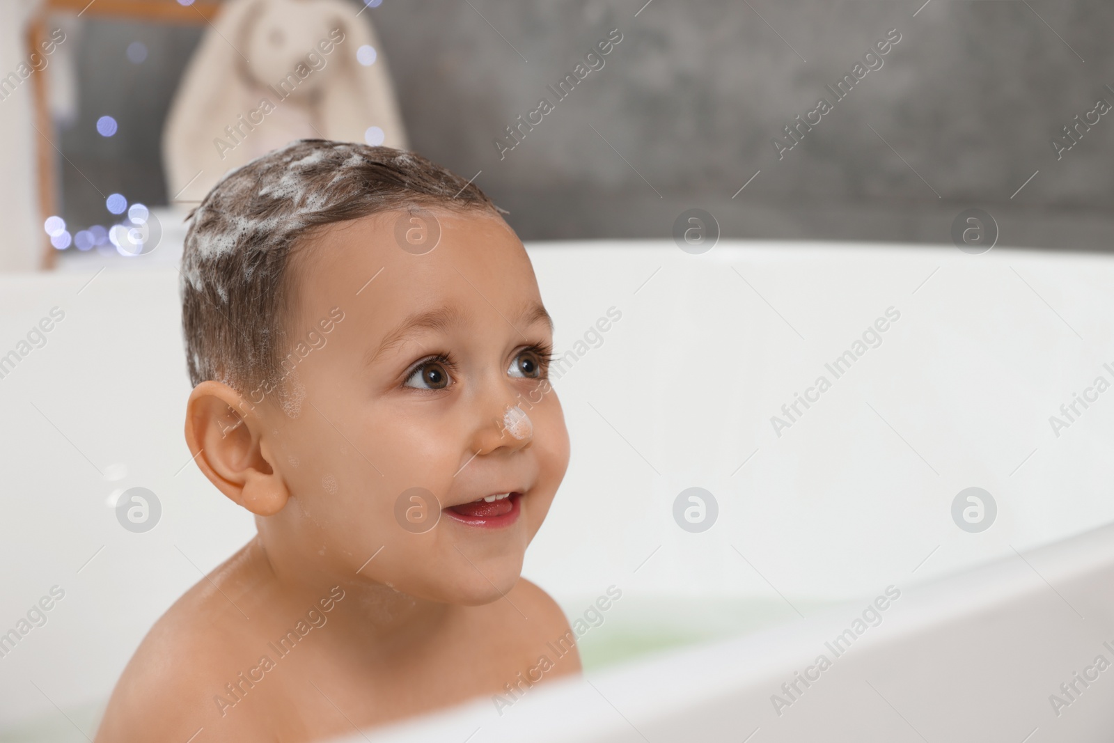 Photo of Cute little boy washing hair with shampoo in bathroom. Space for text