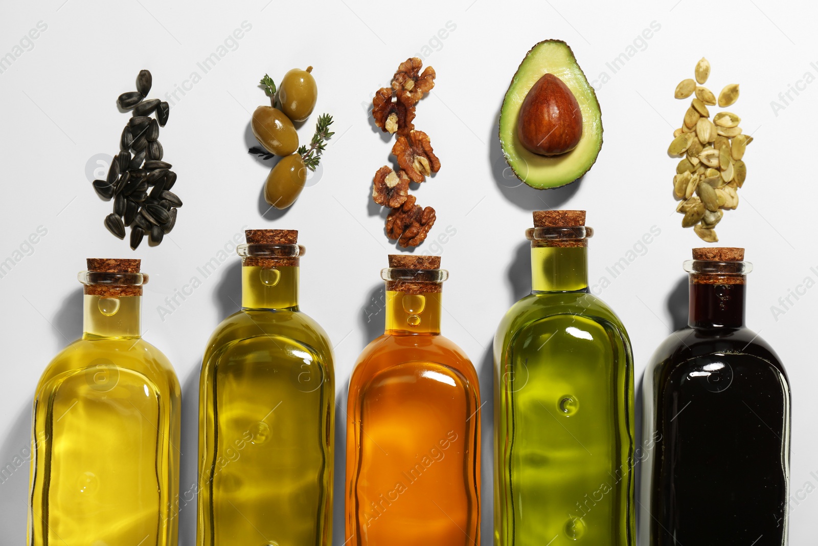 Photo of Vegetable fats. Different cooking oils in glass bottles and ingredients on white background, flat lay