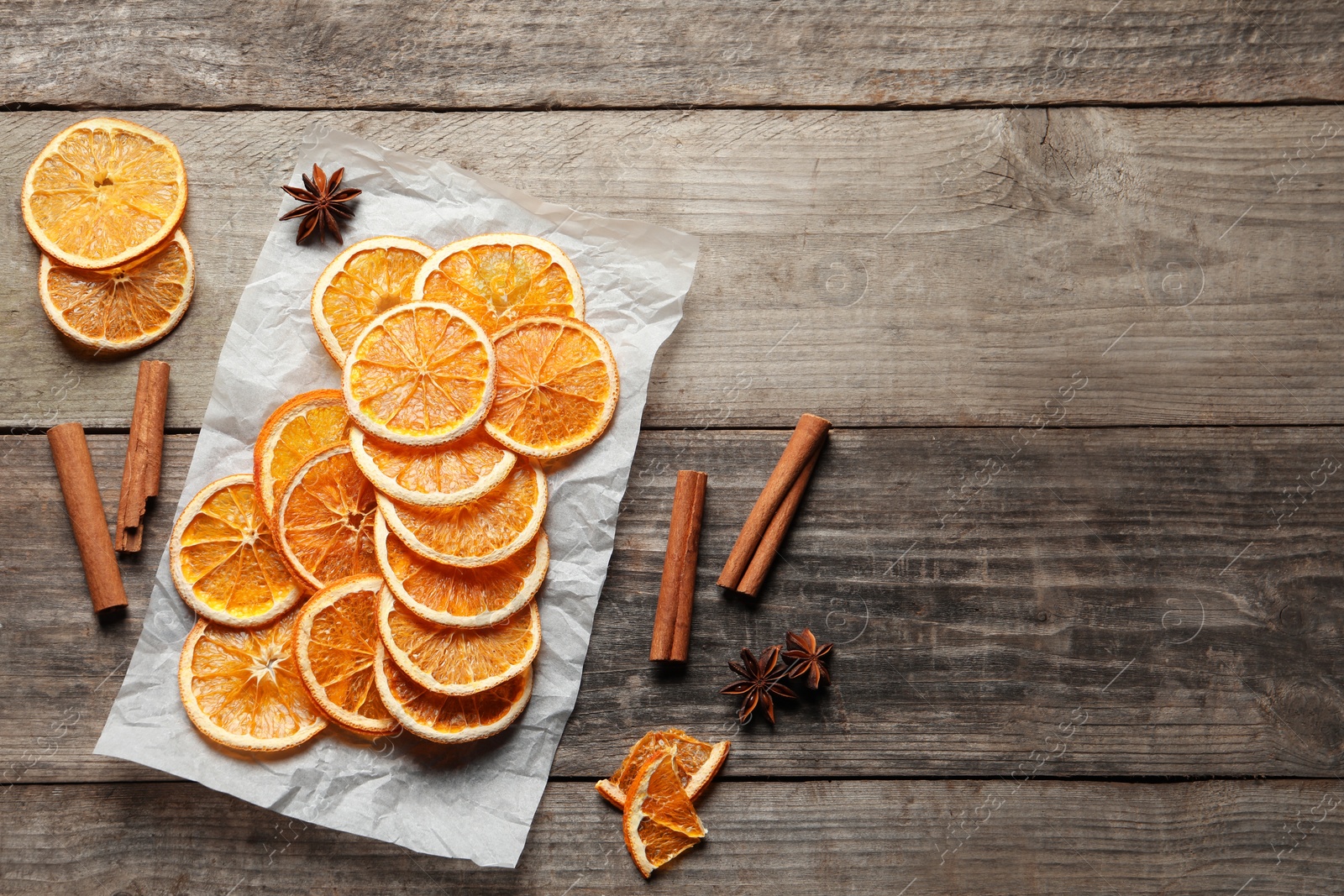 Photo of Many dry orange slices and spices on wooden table, flat lay. Space for text