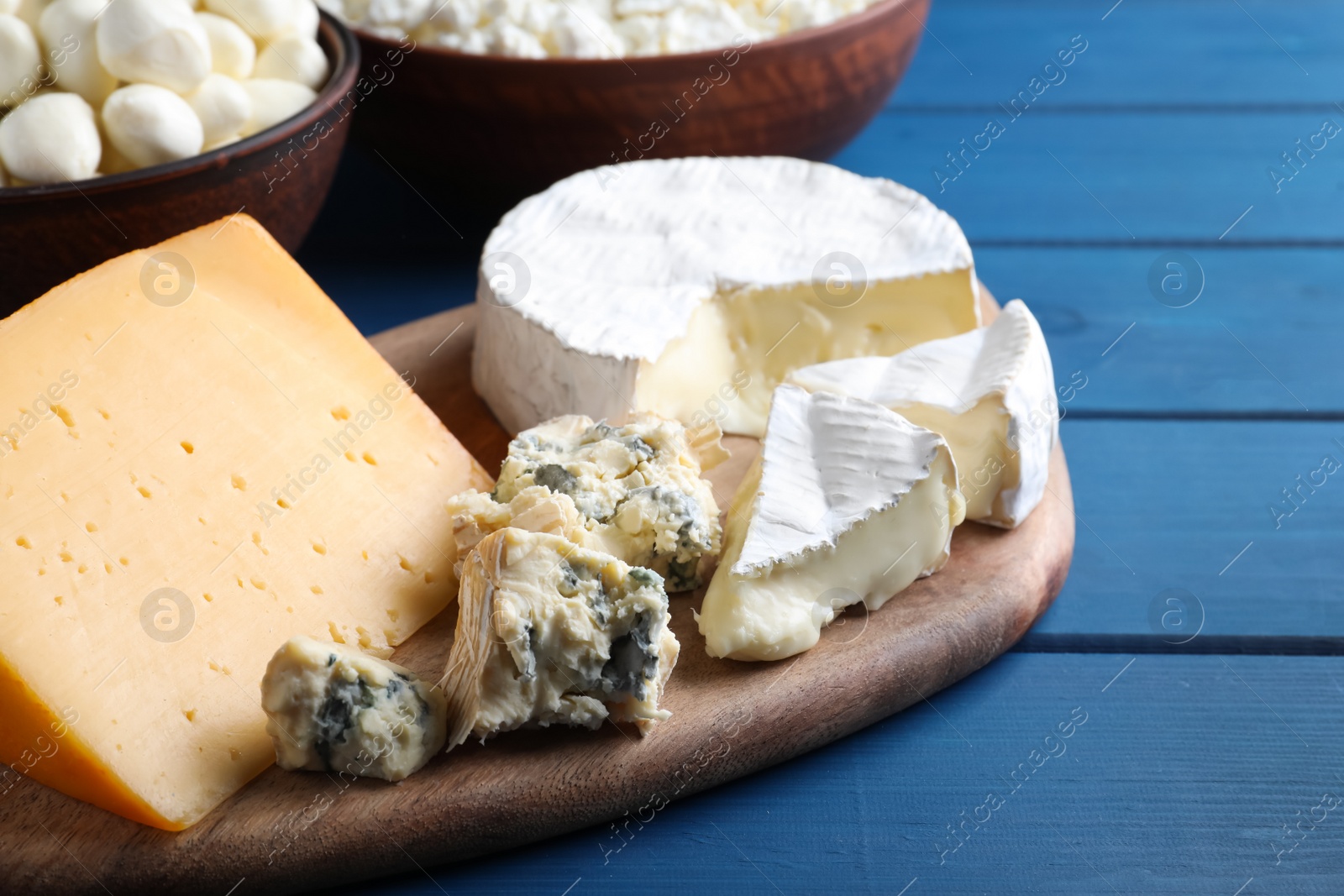 Photo of Fresh dairy products near clay dishware on blue wooden table