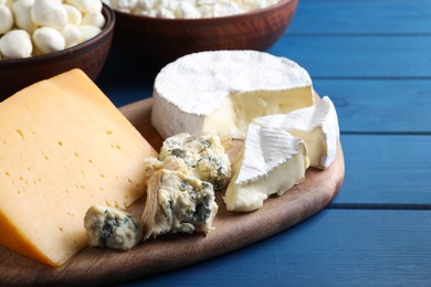 Fresh dairy products near clay dishware on blue wooden table