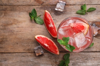 Glass of refreshing drink with grapefruit and mint on wooden table, flat lay. Space for text