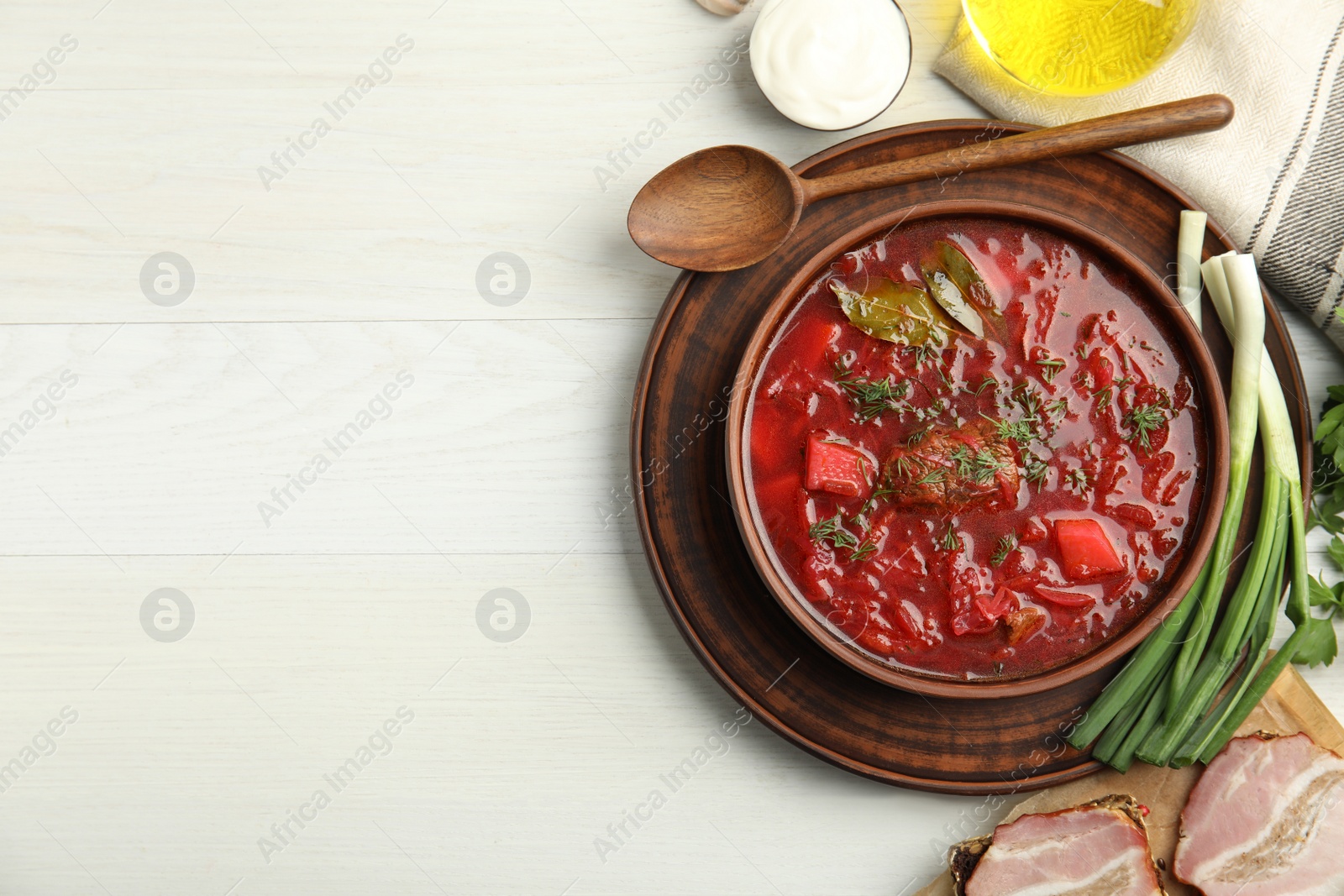 Photo of Stylish brown clay bowl with Ukrainian borsch served on white wooden table, flat lay. Space for text