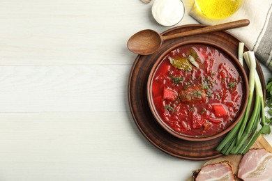 Stylish brown clay bowl with Ukrainian borsch served on white wooden table, flat lay. Space for text