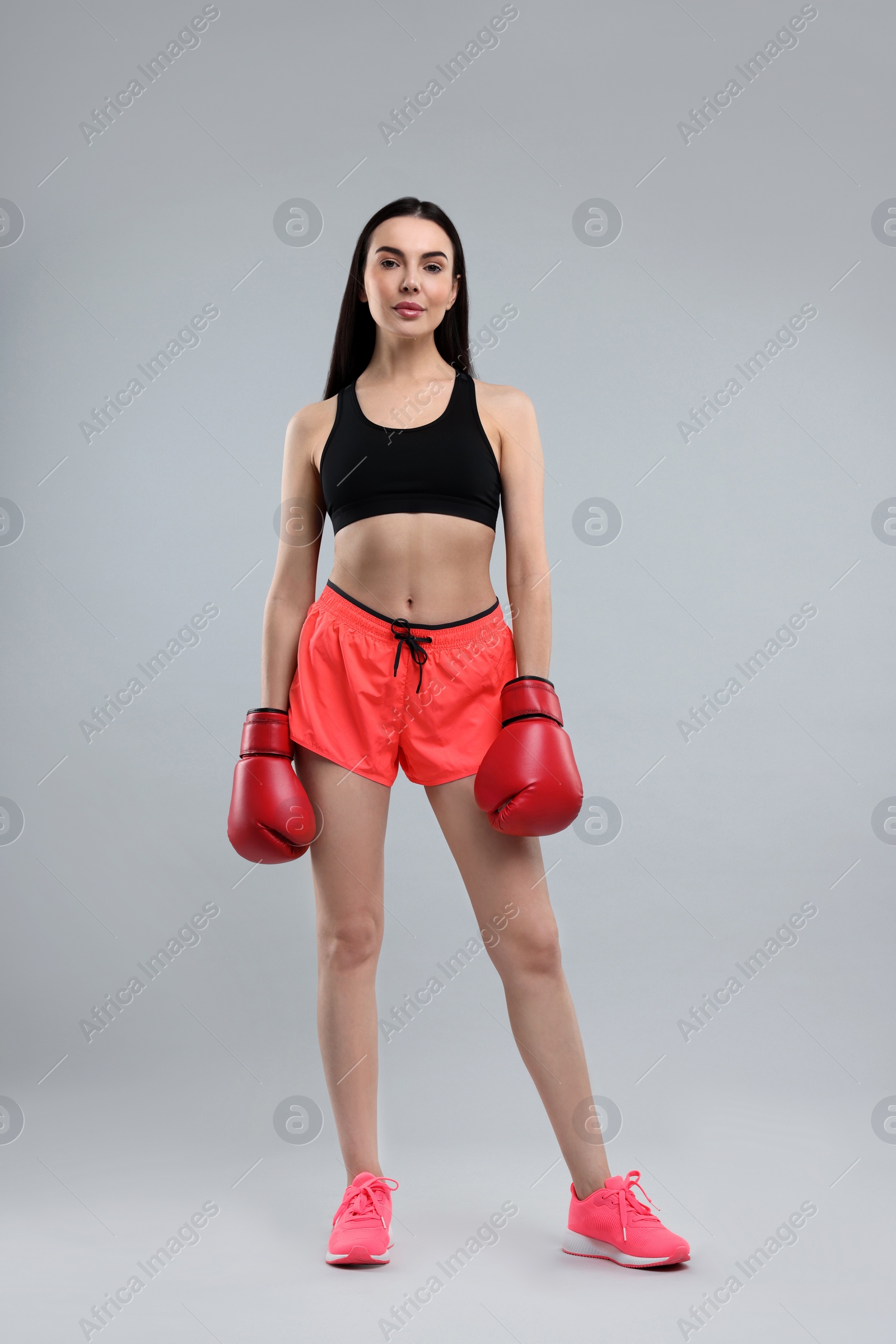 Photo of Beautiful woman in boxing gloves on grey background