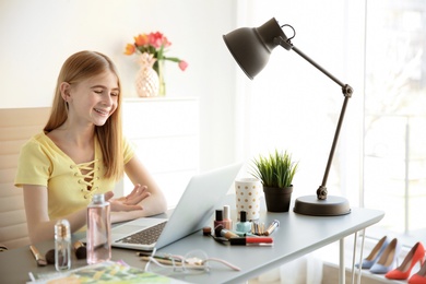 Photo of Cute teenage blogger with laptop and different cosmetics at table