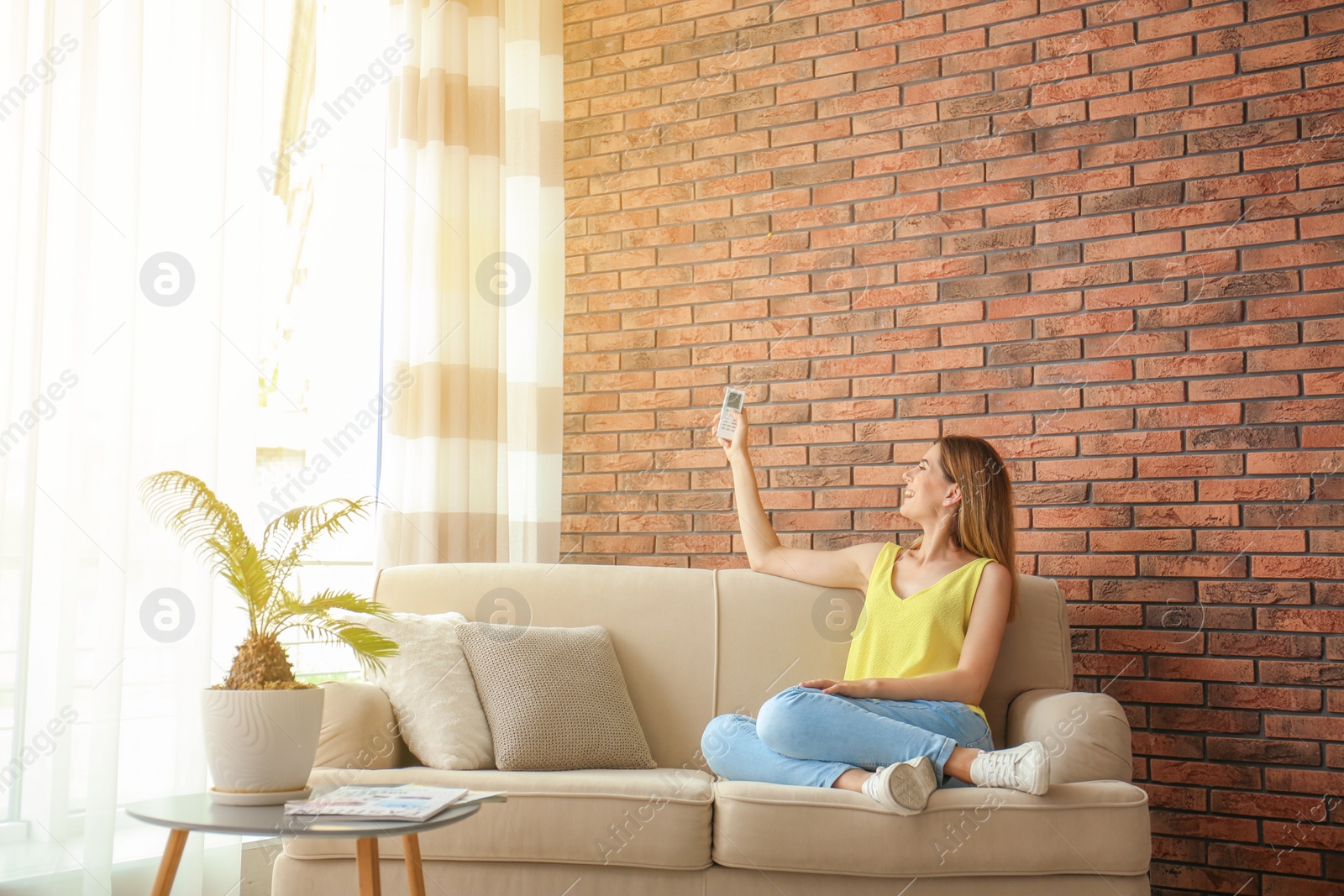 Photo of Woman with air conditioner remote at home