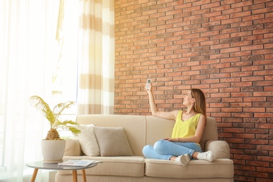 Woman with air conditioner remote at home