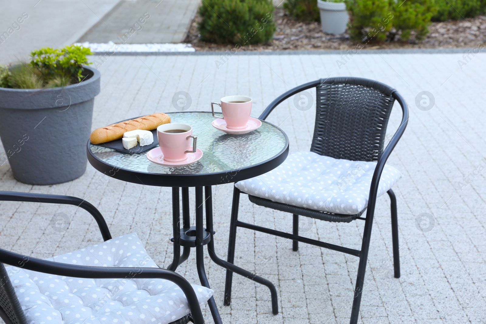 Cups of coffee, bread and cheese on glass table. Relaxing place at outdoor terrace Photo of Cups of coffee, bread and cheese on glass table. Relaxing place at outdoor terrace