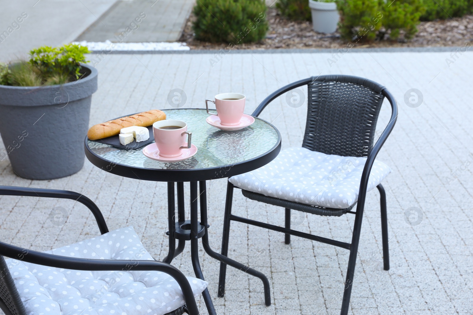 Photo of Cups of coffee, bread and cheese on glass table. Relaxing place at outdoor terrace