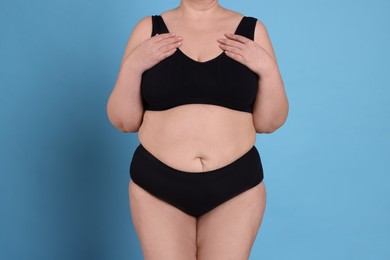 Overweight woman in underwear on light blue background, closeup