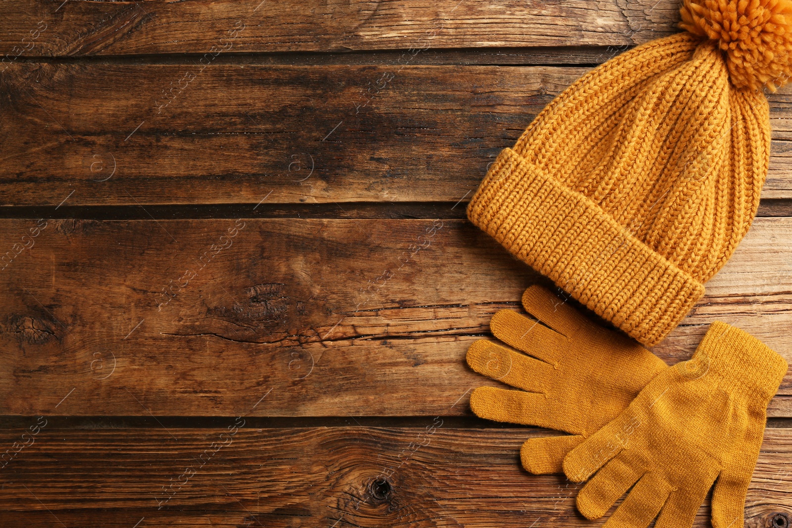 Photo of Stylish gloves and hat on wooden background, flat lay. Space for text