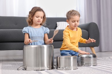 Little children pretending to play drums on pots at home