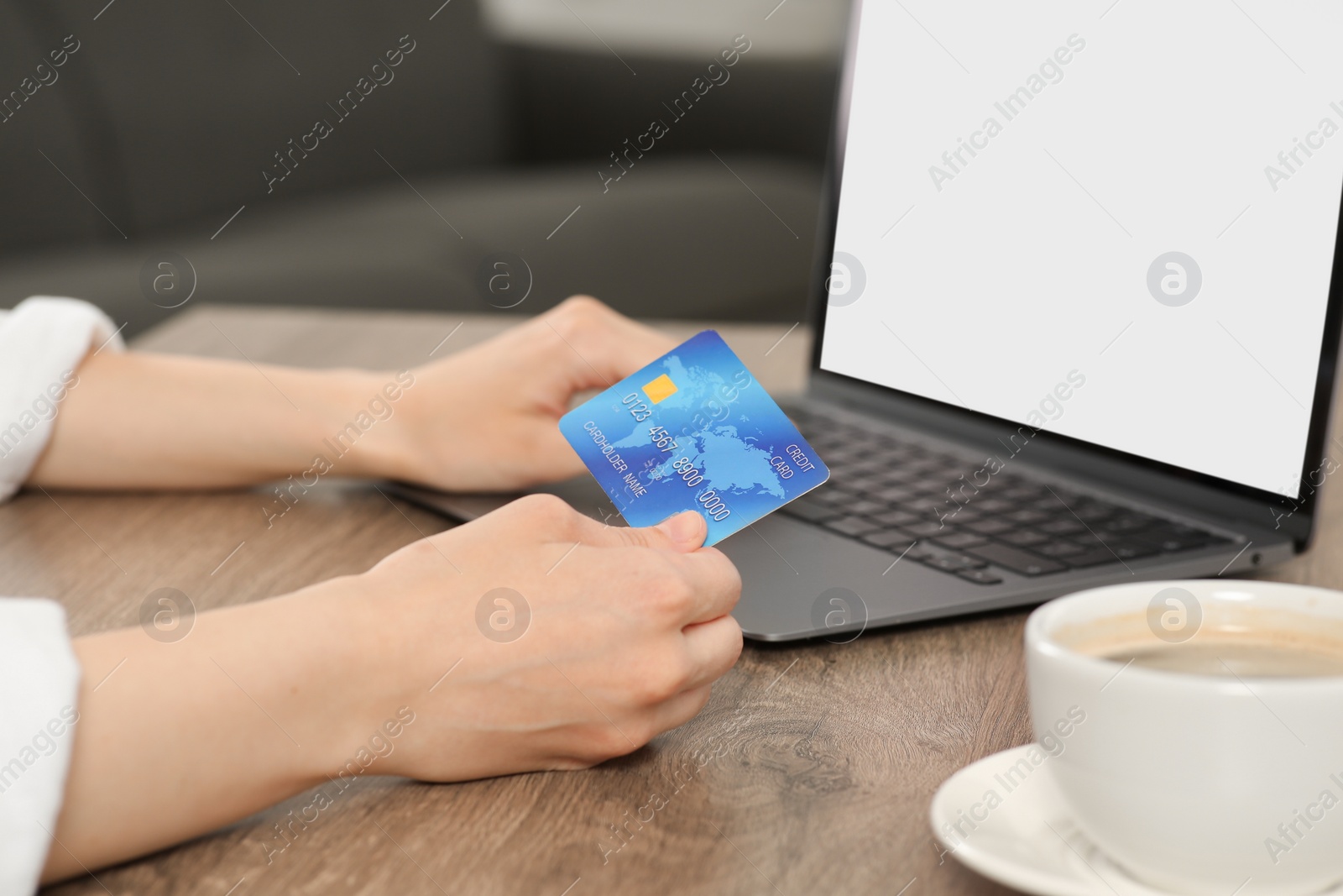 Photo of Woman with credit card using laptop for online shopping at wooden table indoors, closeup