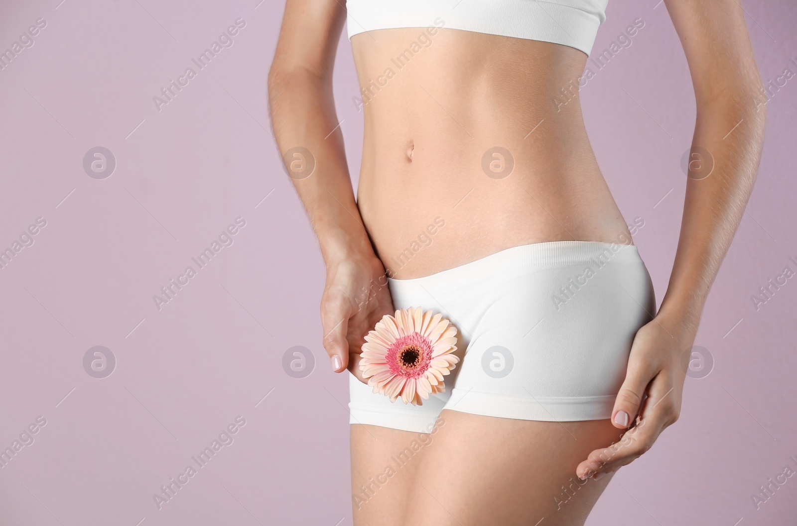 Photo of Young woman with gerbera flower on color background. Gynecology concept