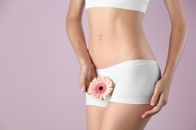 Photo of Young woman with gerbera flower on color background. Gynecology concept