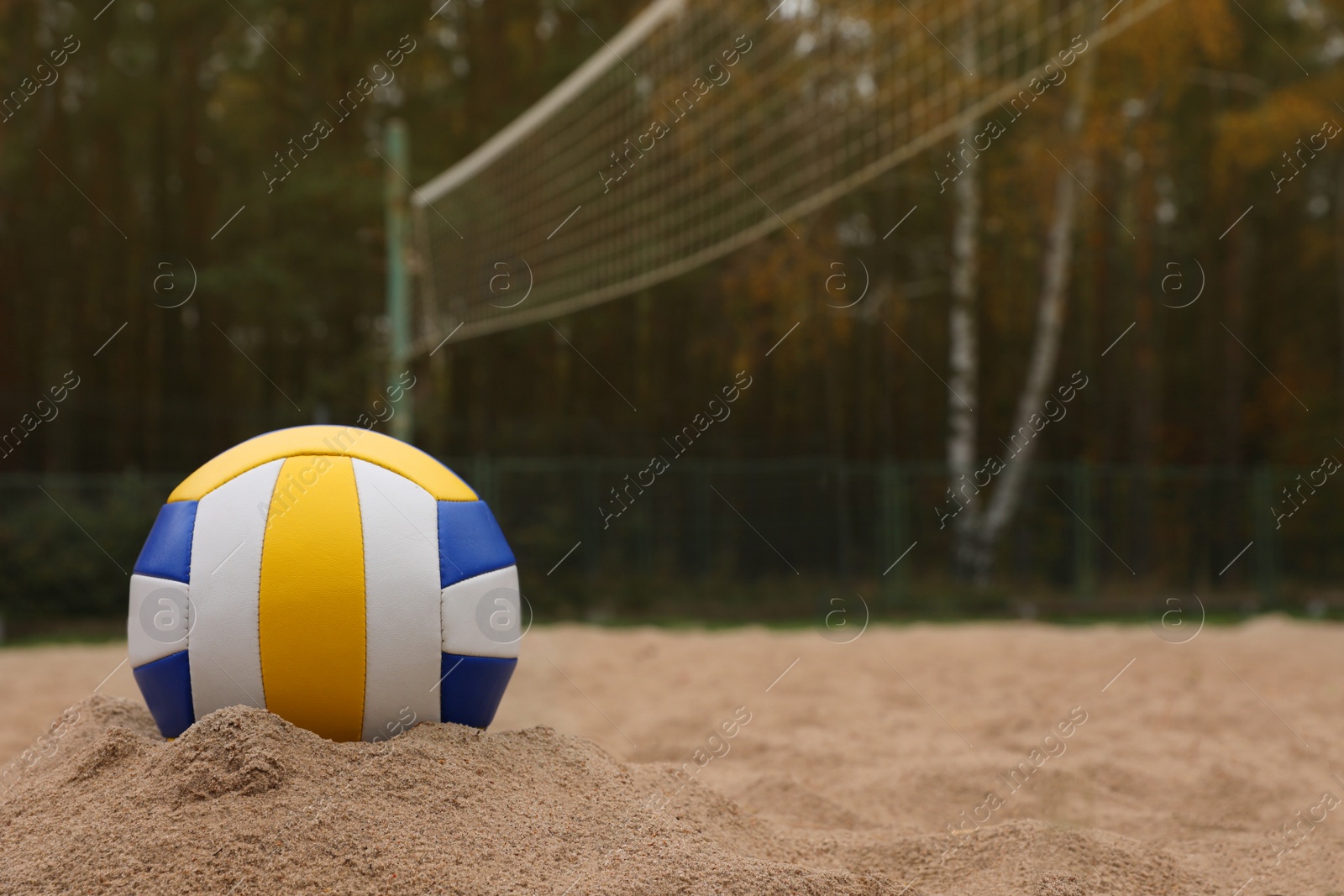 Photo of Colorful volleyball ball on sand court, space for text