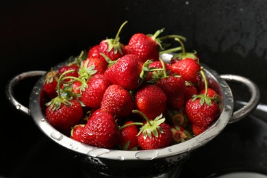 Photo of Metal colander with fresh wet strawberries in sink, closeup